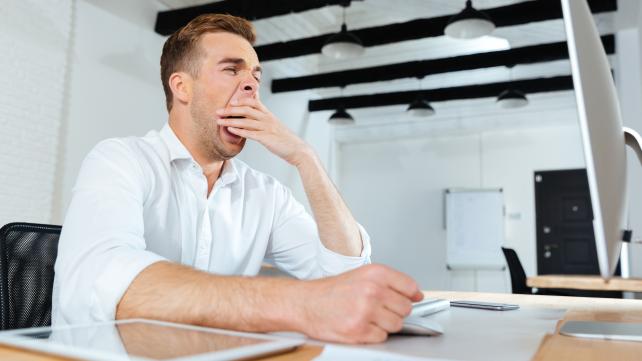 In this image a young man yawing from the the fatigue of overburden